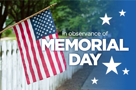 An American flag hanging over a white picket fence near trees in a neighborhood with Memorial Day text.