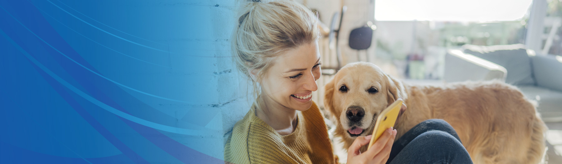 Young woman sitting with her dog, looking at her mobile phone