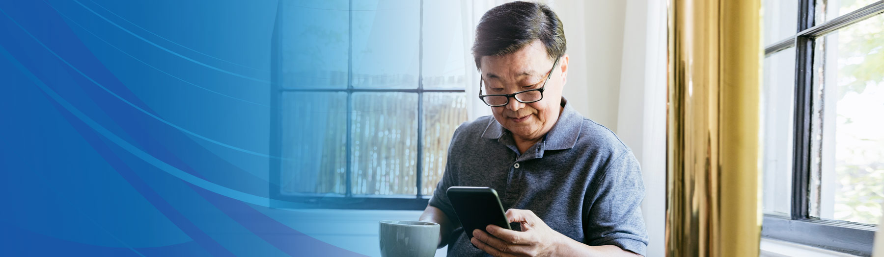 Middle-aged man drinking coffee and looking at his mobile phone