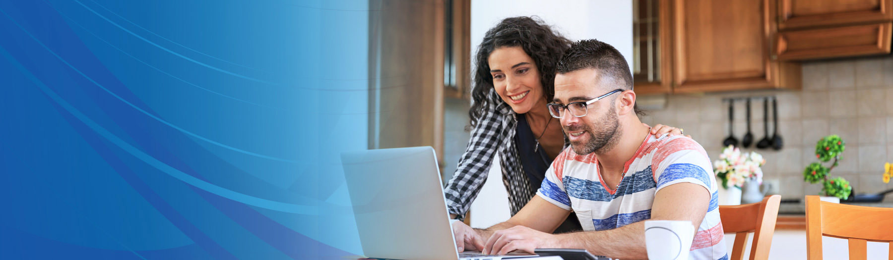 Happy man and woman in a kitchen looking at a laptop computer screen