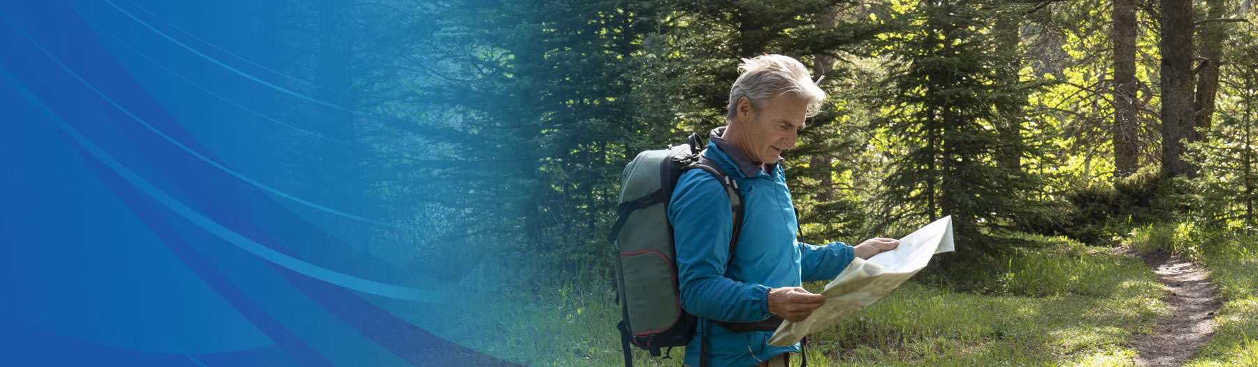 Male hiker in the woods looking at his map