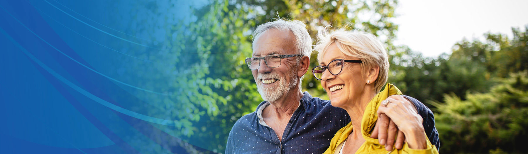 A middle-aged couple standing together near a grove of trees