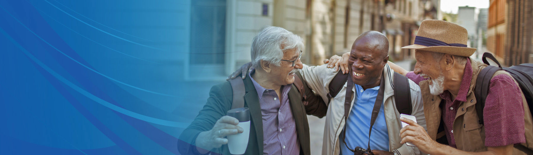 Three older male tourists enjoying coffee, talking, and laughing outside