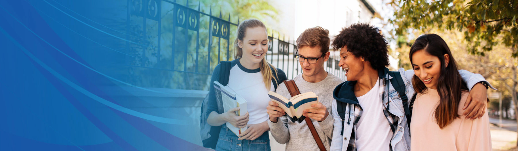 Four teenagers walking and discussing a book outside school grounds