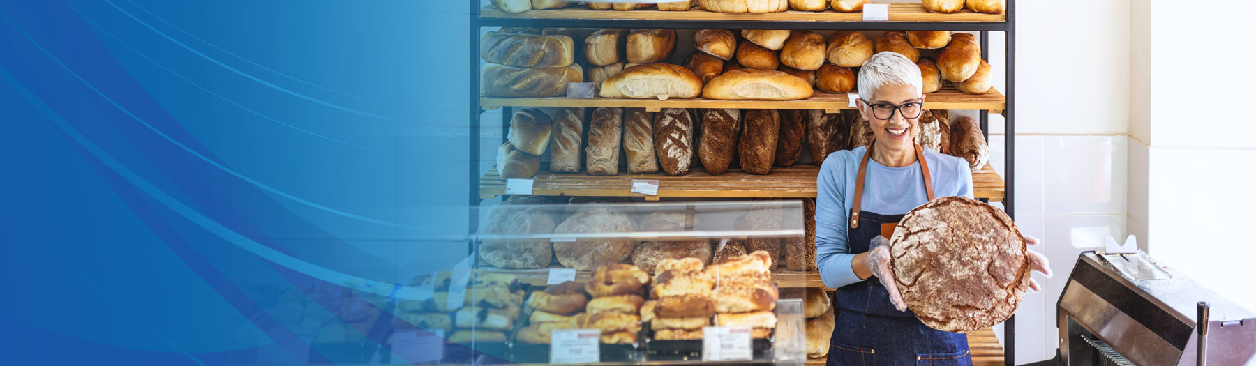 Female baker holding a loaf of artisan bread in her bakery