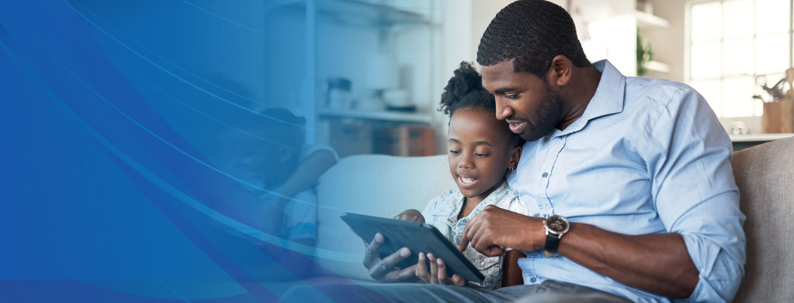 A father and daughter sitting on the couch looking at a tablet